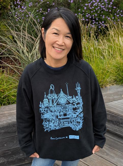 Daisy Nguyen wearing a black sweatshirt with blue line art.